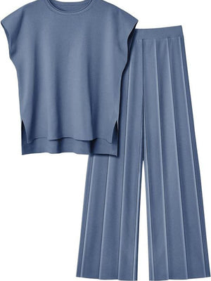 a woman wearing a blue top and pleated pants