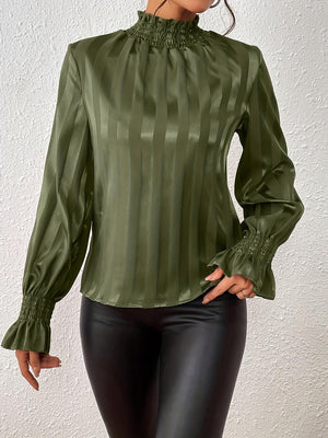 a woman wearing a green blouse and black pants