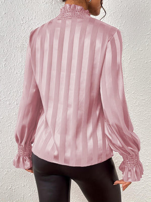 a woman wearing a pink blouse and black pants