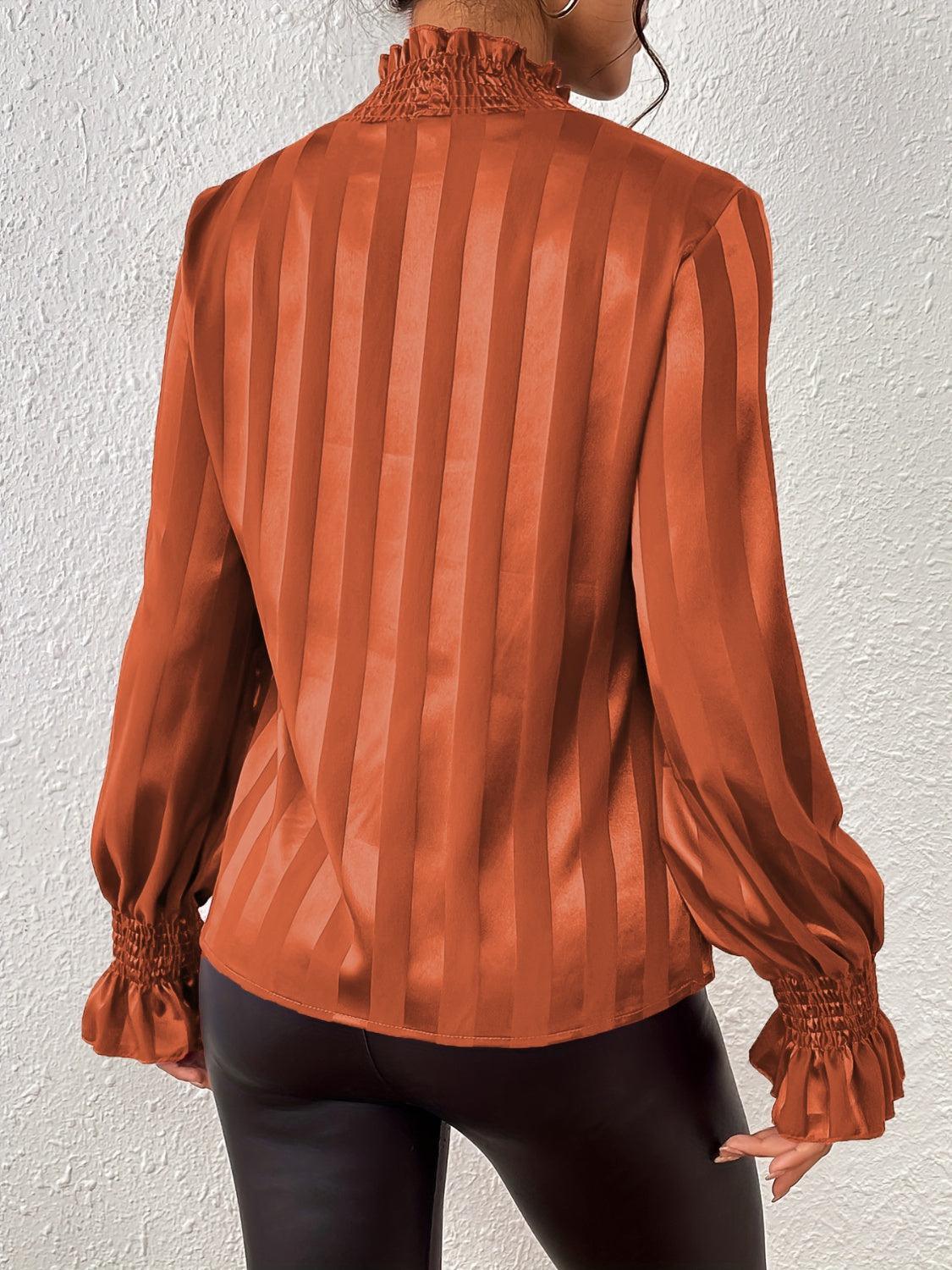 a woman wearing an orange blouse and black pants