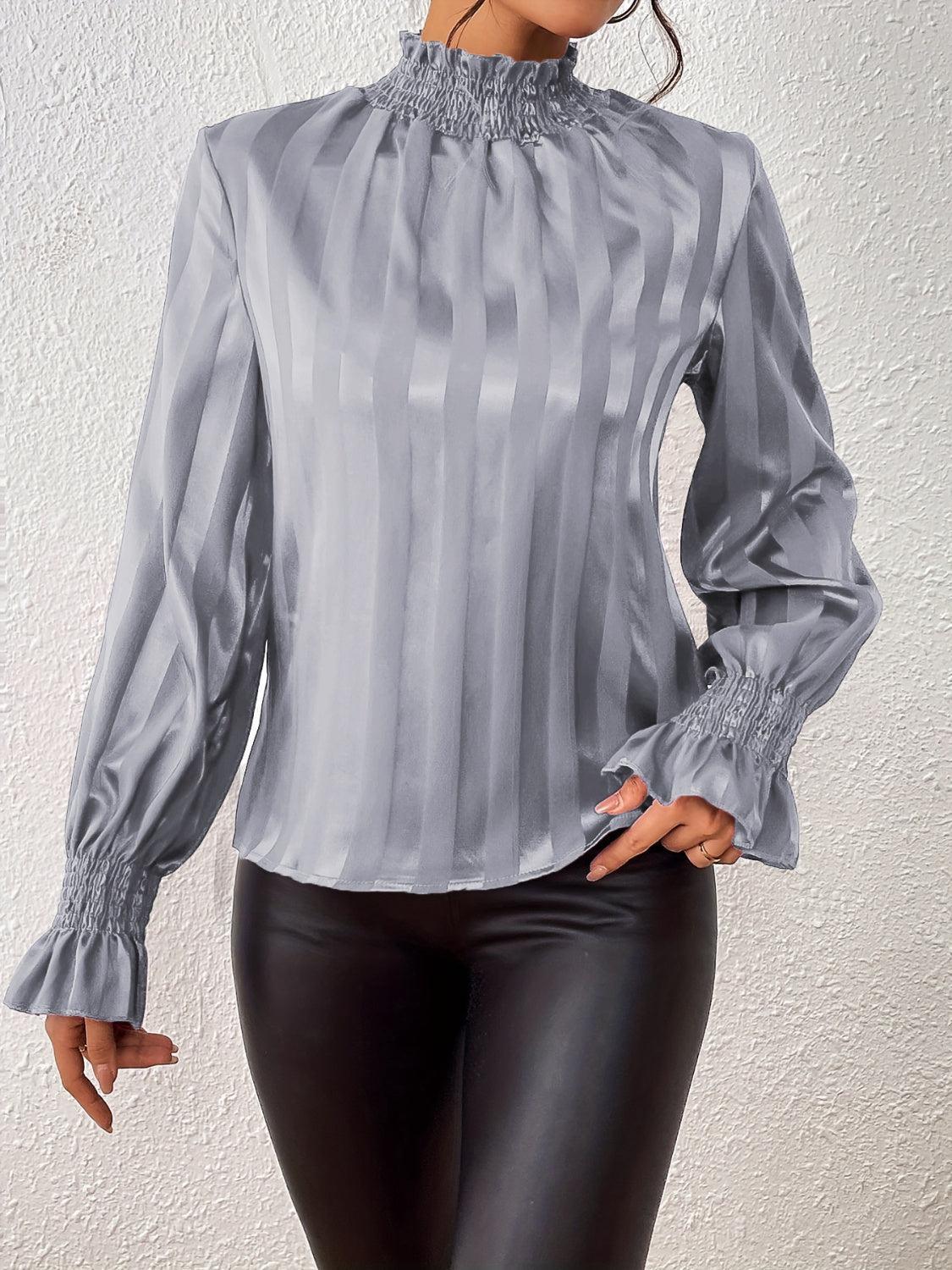 a woman wearing a silver blouse and black pants