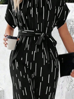 a woman in a black and white jumpsuit holding a cup of coffee