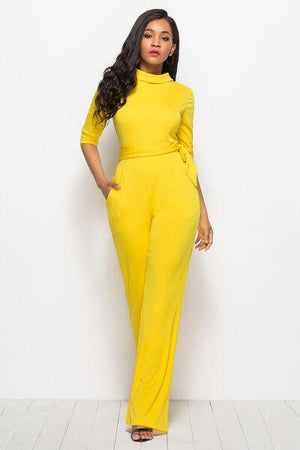 a woman in a yellow jumpsuit posing for a picture