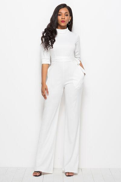 a woman in a white jumpsuit posing for a picture