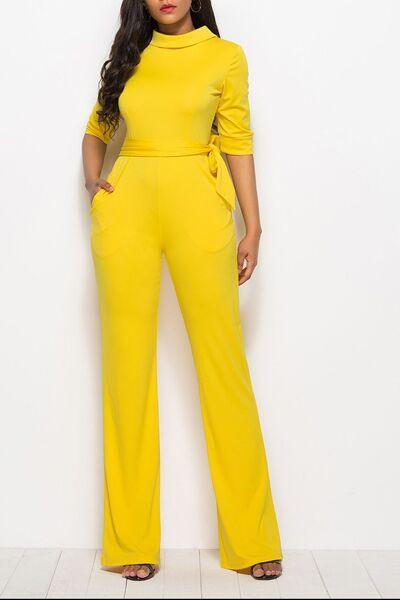a woman in a yellow jumpsuit posing for a picture