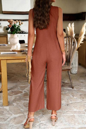 a woman standing in front of a table wearing a brown jumpsuit