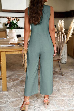 a woman standing in front of a table wearing a green jumpsuit