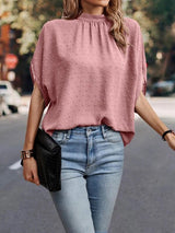 a woman walking down a street wearing a pink top