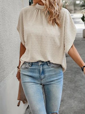 a woman wearing ripped jeans and a beige top