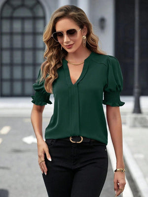 a woman wearing a green blouse and black pants