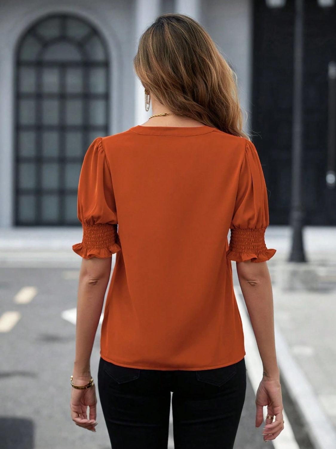 a woman in an orange top is walking down the street
