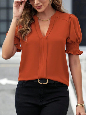 a woman in an orange blouse and black pants