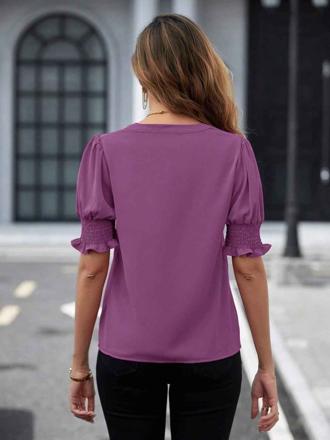 a woman walking down a street wearing a purple top