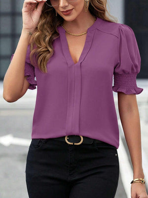 a woman wearing a purple blouse and black pants