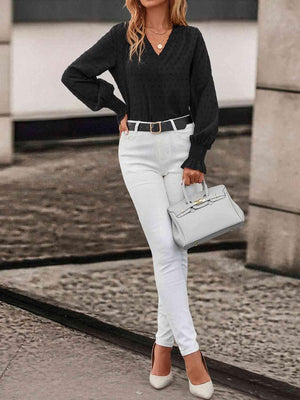 a woman wearing white pants and a black sweater