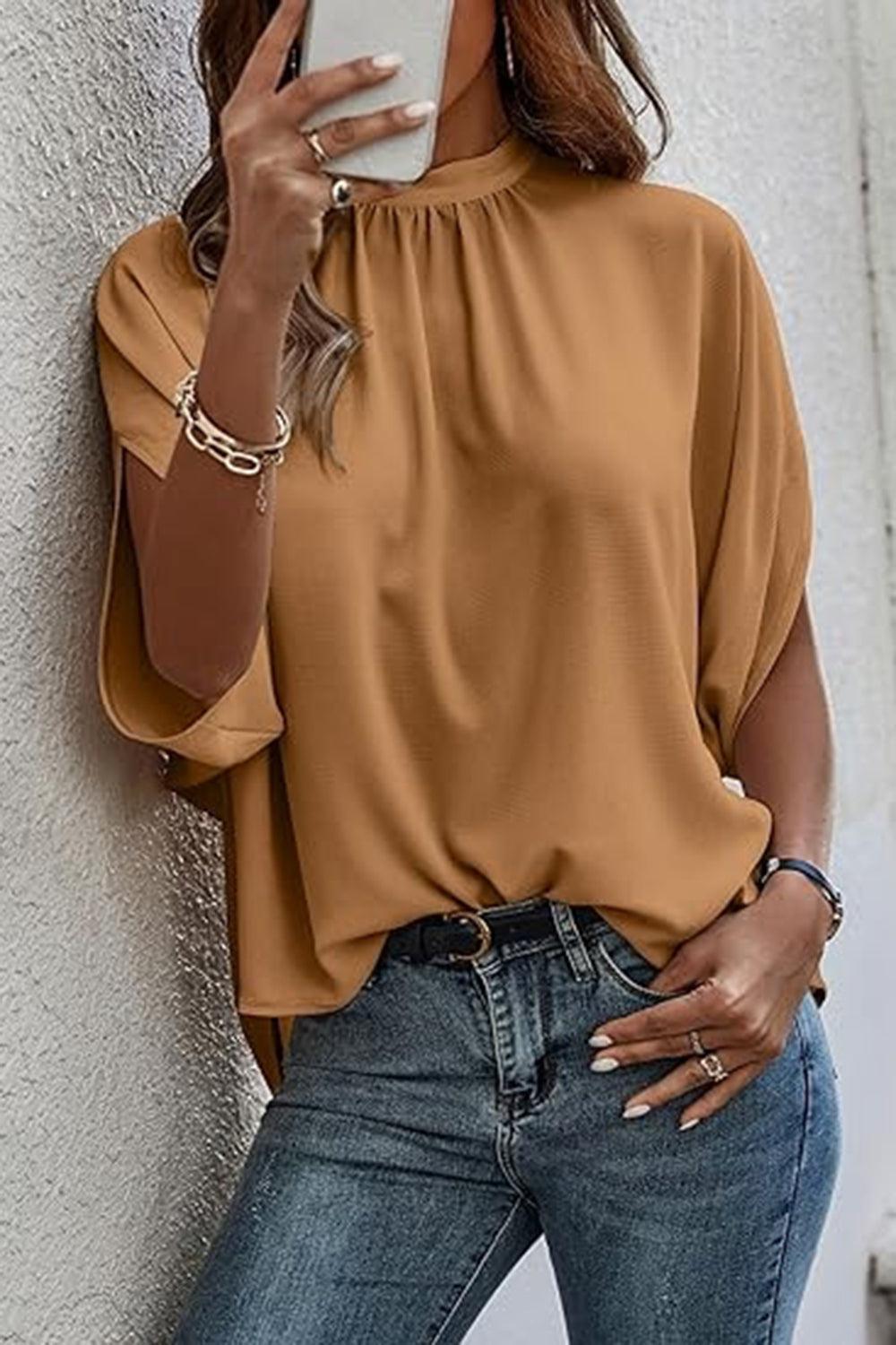 a woman standing against a wall holding a cell phone