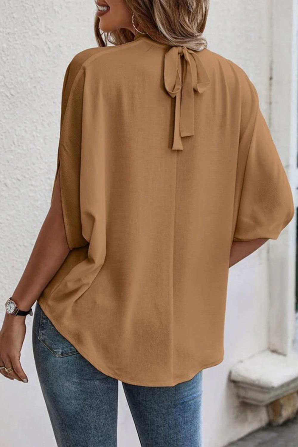 a woman wearing a brown blouse and jeans