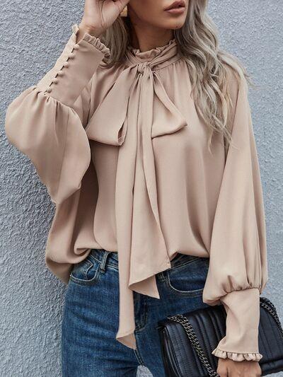 a woman wearing a beige blouse and jeans