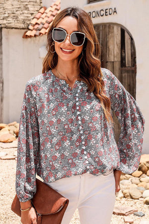 a woman wearing a floral blouse and white pants