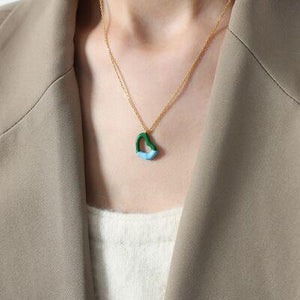 a woman wearing a necklace with a green and blue pendant