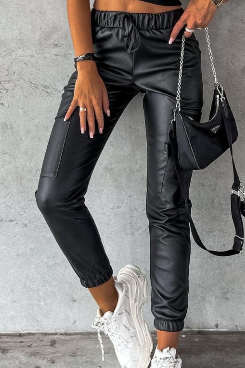 a woman wearing black leather pants and white sneakers