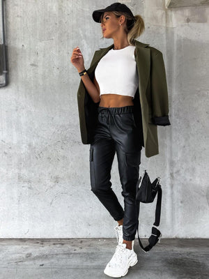 a woman wearing black leather pants and a white crop top