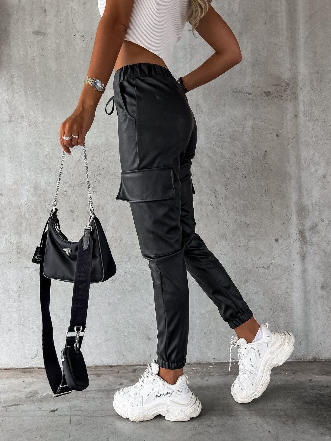 a woman in white shirt and black pants holding a black purse