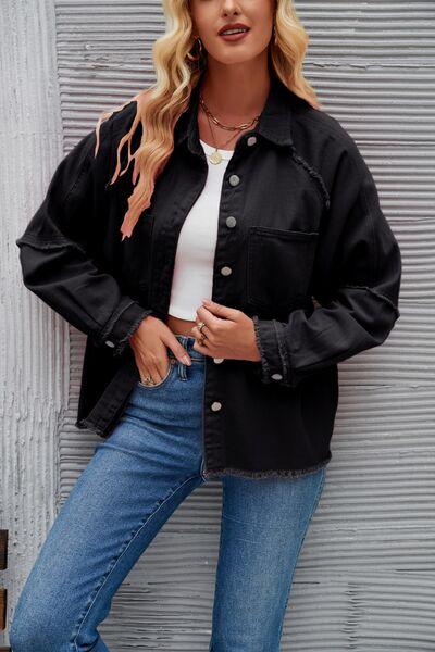 a woman wearing a black jacket and jeans leaning against a wall