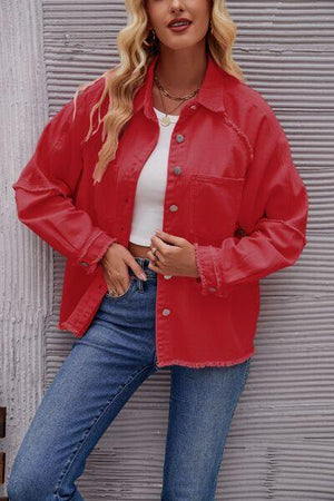 a woman in a red jacket leaning against a wall