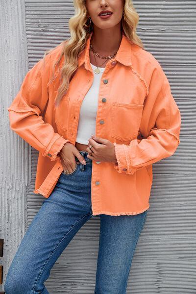 a woman in an orange jacket leaning against a wall