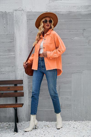 a woman in an orange jacket and hat standing next to a bench