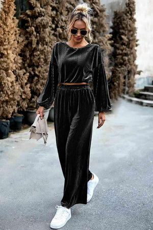 a woman wearing a black velvet jumpsuit and white sneakers
