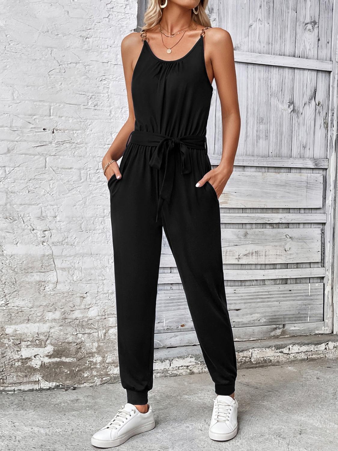 a woman wearing a black jumpsuit and white sneakers