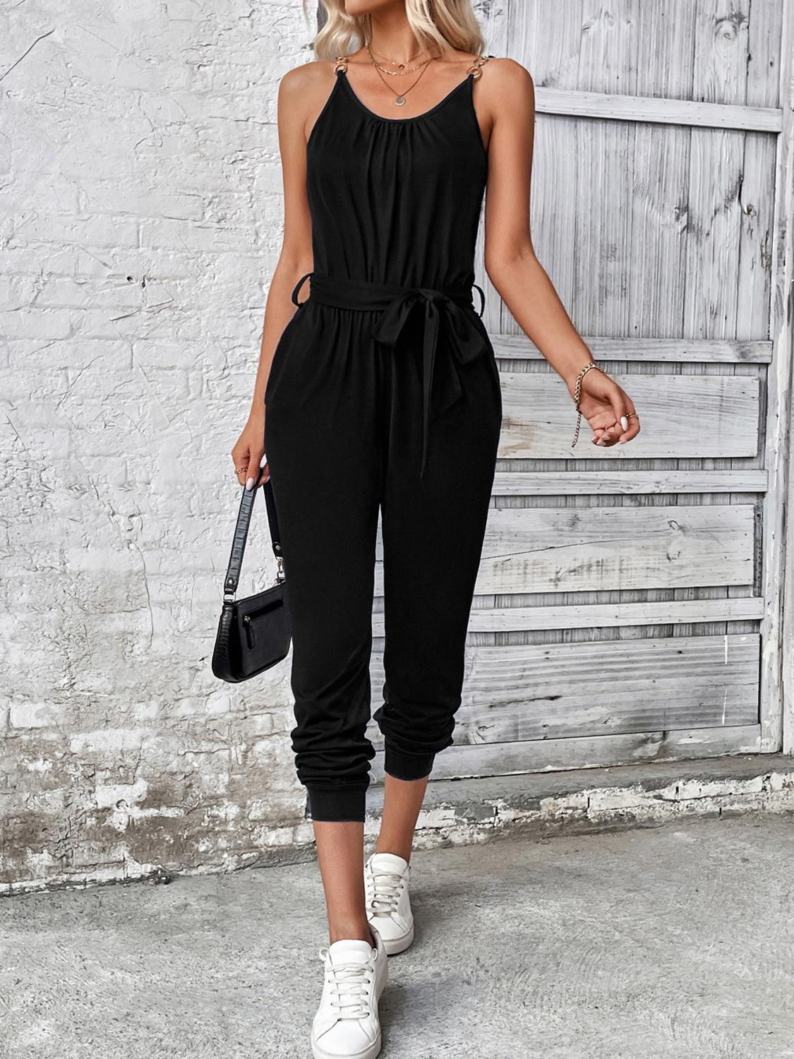 a woman wearing a black jumpsuit and white sneakers