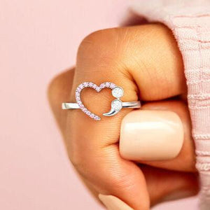 a woman's hand holding a heart shaped ring