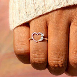 a woman's hand with a heart shaped ring on it