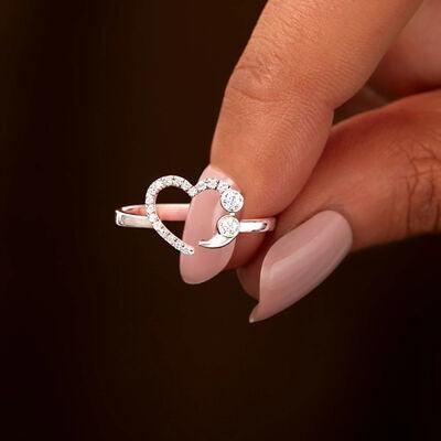 a woman's hand holding a ring with a heart on it