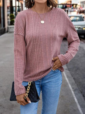 a woman wearing a pink sweater and jeans