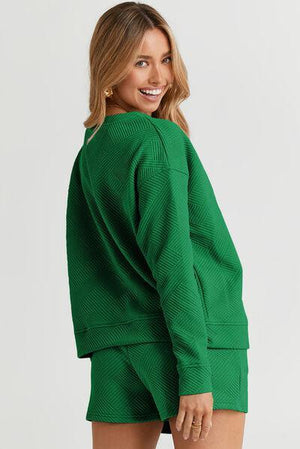 a woman wearing a green sweater and shorts
