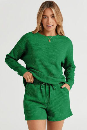 a woman wearing a green sweater and shorts