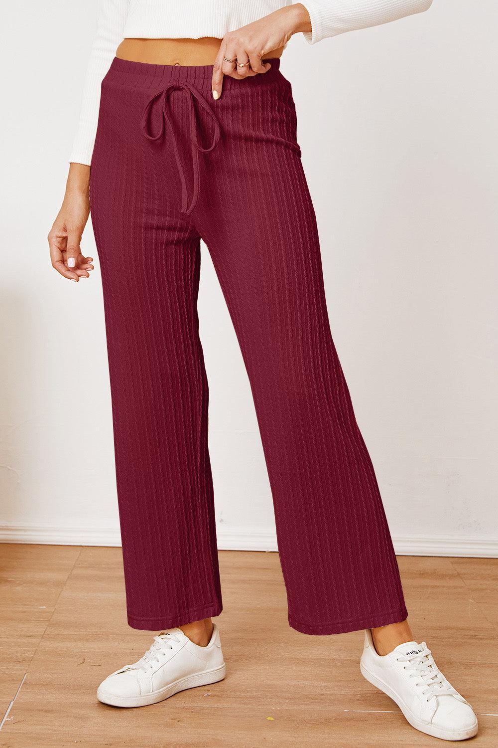 a woman in a white top and maroon pants