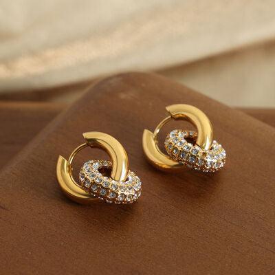 a pair of gold and diamond earrings on a brown surface