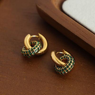 a pair of green and gold earrings sitting on top of a wooden table