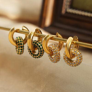 a row of gold and green earrings hanging from a gold bar