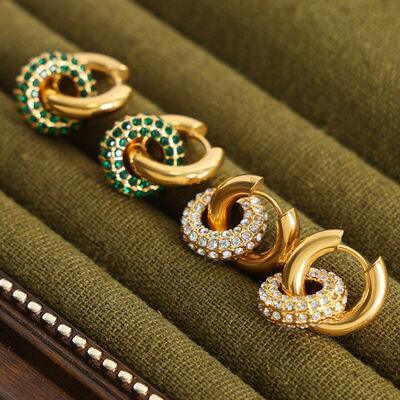 three pairs of earrings sitting on top of a green cushion