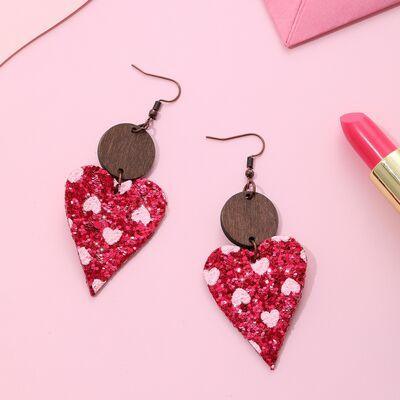a pair of heart shaped earrings sitting on top of a pink table