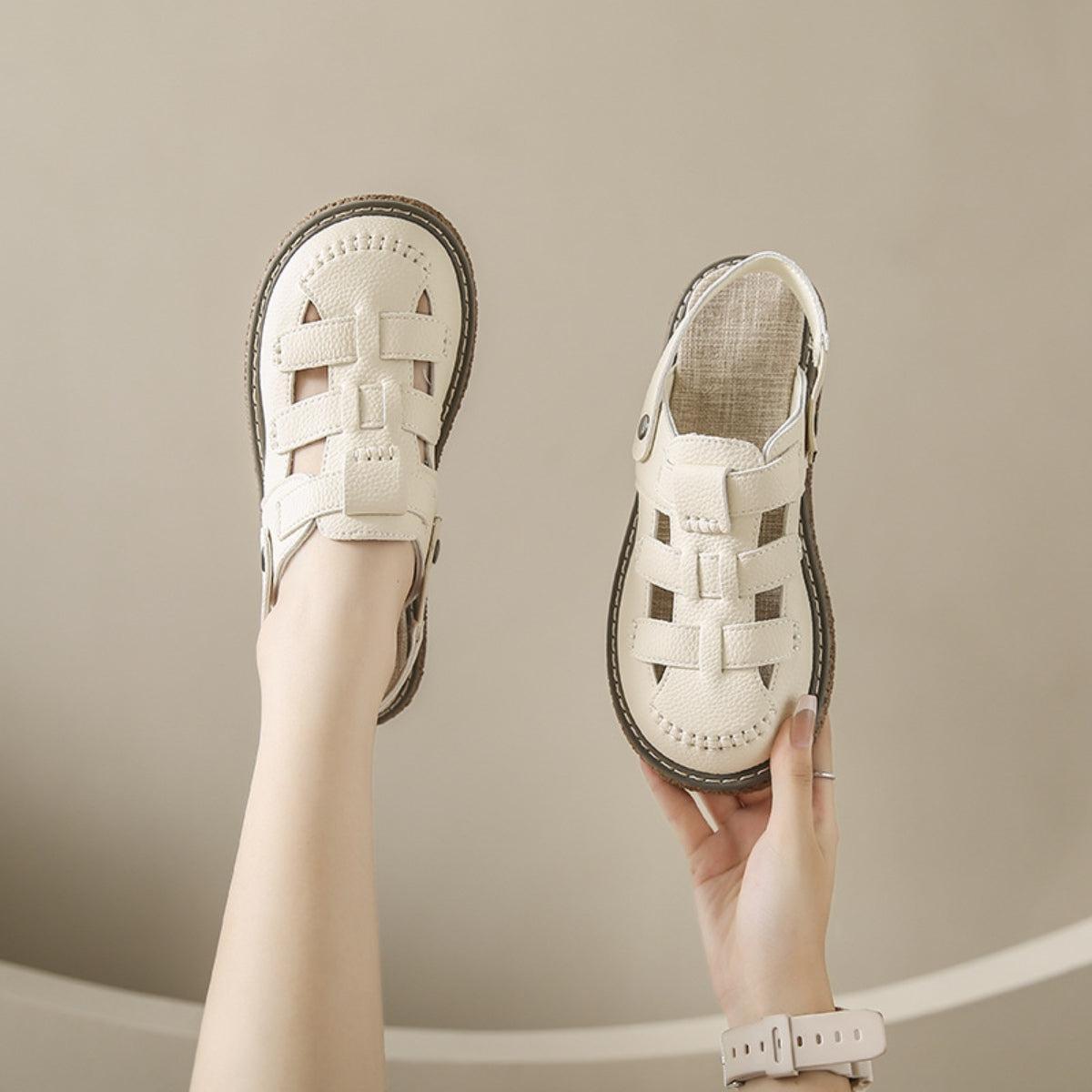 a woman's hand holding a pair of white shoes