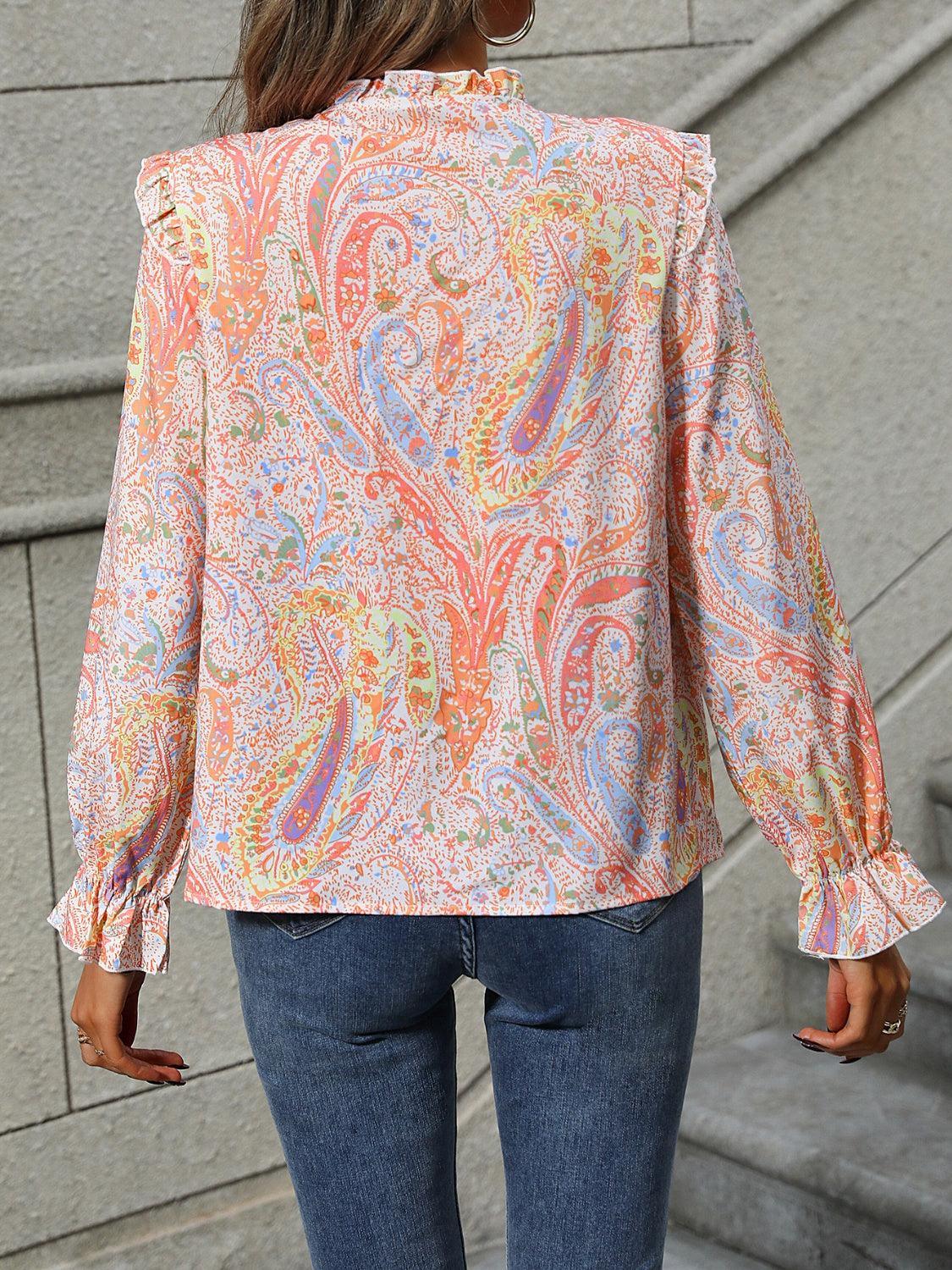 a woman wearing a paisley blouse and jeans