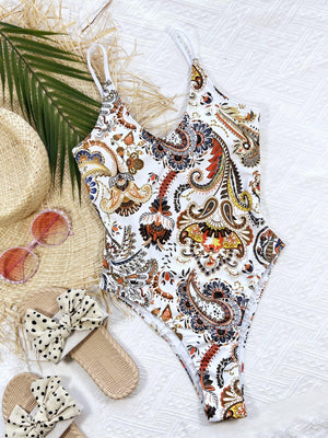 a bathing suit, hat, sunglasses, and flip flops are laid out on