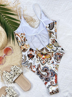 a white swimsuit and a straw hat on a bed